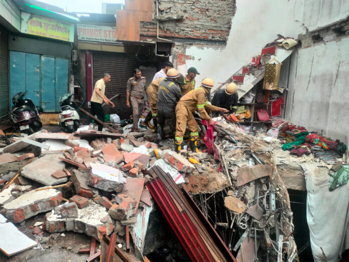 आगरा के सुभाष बाजार में बारिश के दौरान गिरी कपड़ों की दुकान के मलबे में राहत-बचाव अभियान चलाती पुलिस और दमकल की टीम।